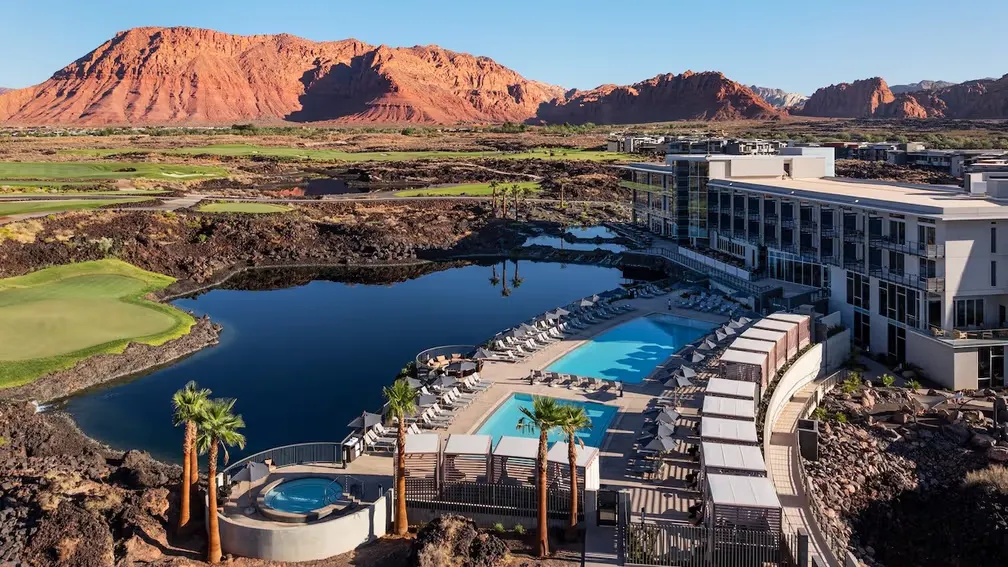 Aerial view of Black Desert Resort's pools and lake, with lava fields, golf greens and red cliffs behind