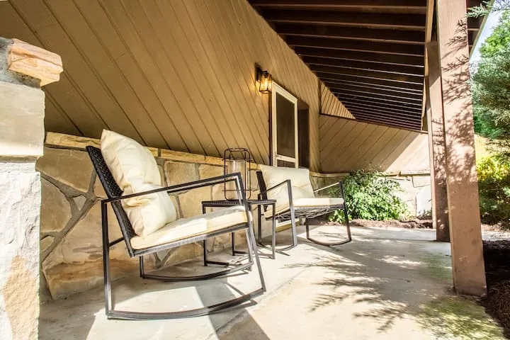 Covered stone porch with two rocking chairs and a lantern
