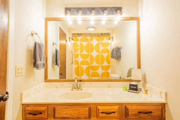 Bathroom vanity with a large mirror and a yellow patterned shower curtain